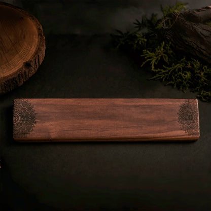 Hand-carved walnut wrist rest with floral pattern, top view on dark background