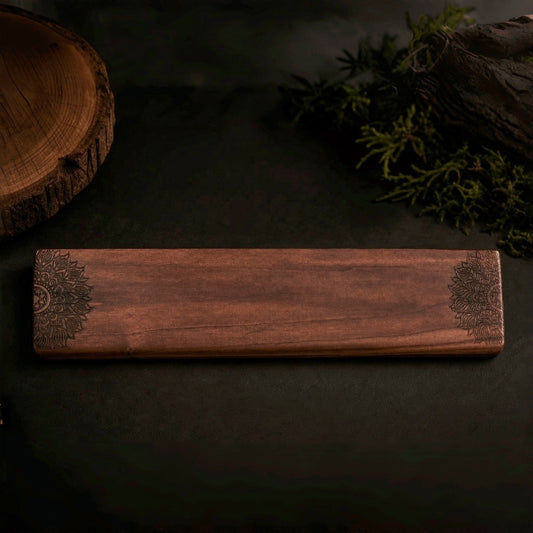 Hand-carved walnut wrist rest with floral pattern, top view on dark background